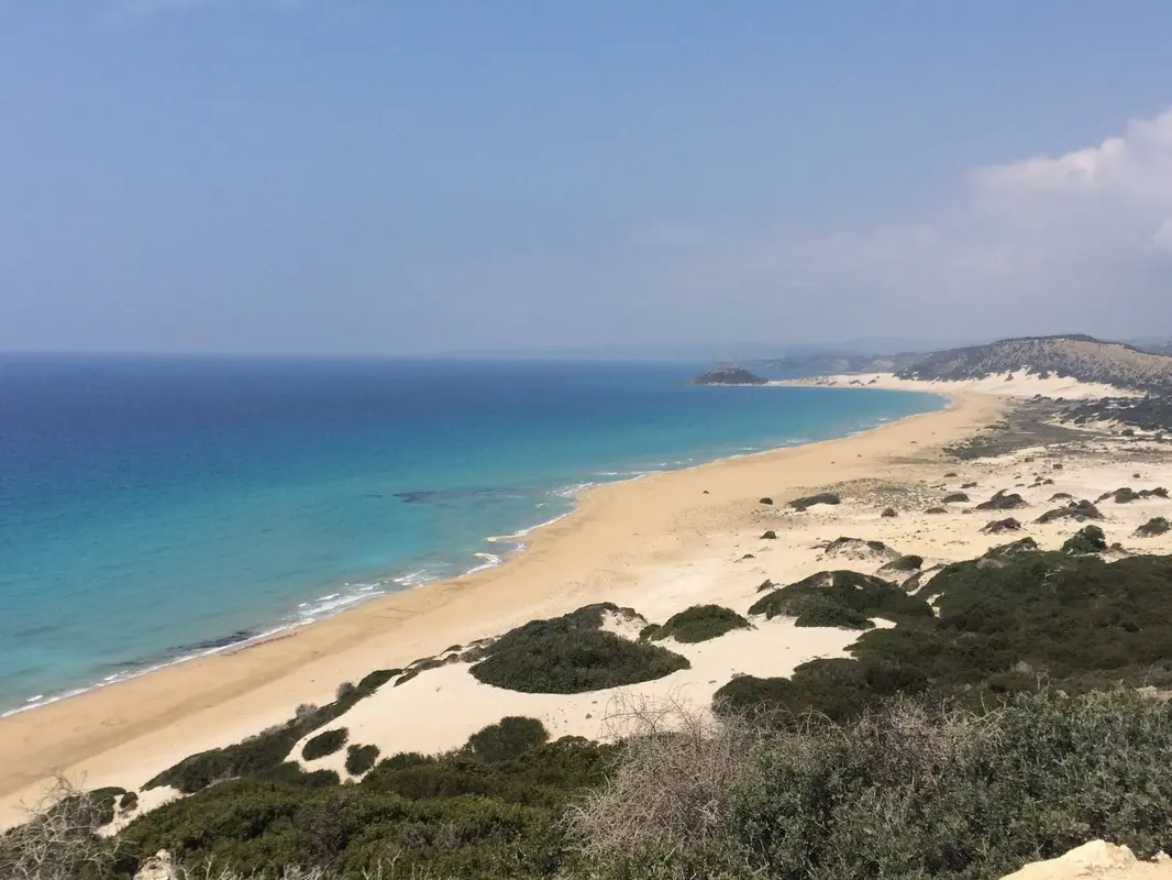 Lang sandstrand med sanddyner og turkis hav