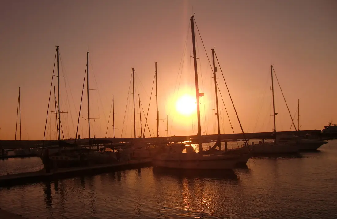 Solnedgang bak seilbåtmaster i havnen